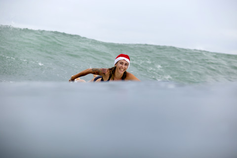 Indonesia, Bali, smiling woman on surfboard wearing Santa hat stock photo