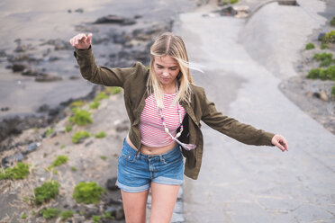 Spain, Tenerife, young blond woman balancing on wall - SIPF01347