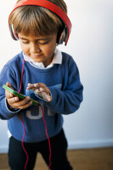 Little boy listening to music of his smartphone with headphones - VABF01052