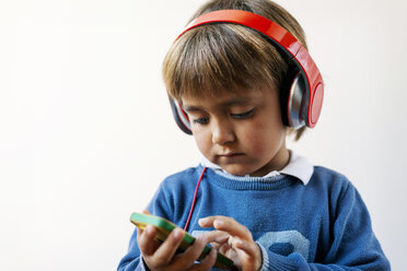 Little boy listening to the music of his smartphone with headphones - VABF01053