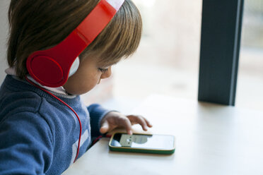 Kleiner Junge hört mit Kopfhörern die Musik seines Smartphones - VABF01057
