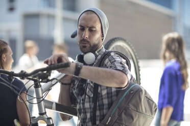 Young man holding bicycle checking the time - ZEF12483