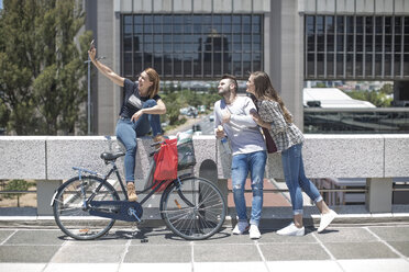 Friends taking a selfie with shopping bags and bicycle in the city - ZEF12489