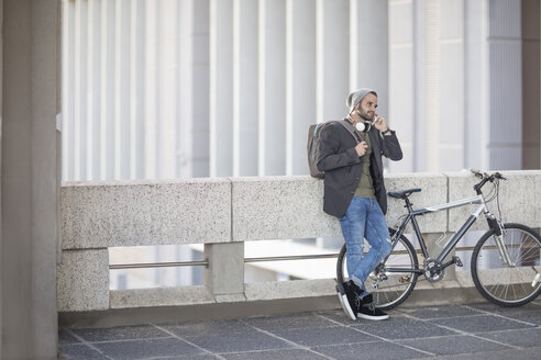 Junger Mann am Handy neben dem Fahrrad - ZEF12490