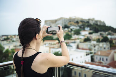 Griechenland, Athen, Frau, die ein Handy-Foto des Parthenon-Tempels auf der Akropolis macht, umgeben von der Stadt - GEMF01397