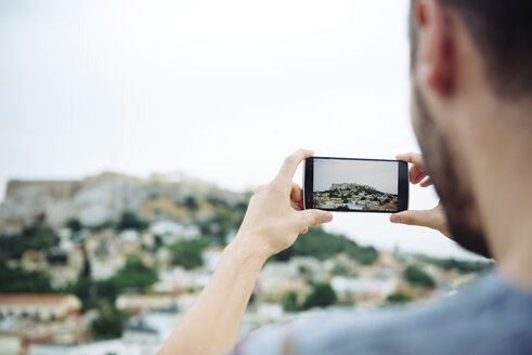 Griechenland, Athen, Mann fotografiert mit seinem Handy den Parthenon-Tempel auf der Akropolis, umgeben von der Stadt - GEMF01398