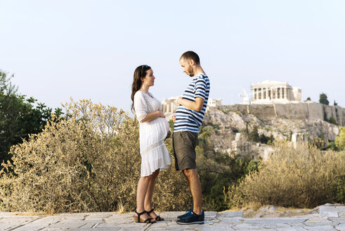 Griechenland, Athen, werdende Eltern zeigen den Bauch auf dem Areopag mit der Akropolis und dem Parthenon im Hintergrund - GEMF01427