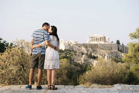 Griechenland, Athen, küssendes Paar auf dem Areopag mit der Akropolis und dem Parthenon im Hintergrund, lizenzfreies Stockfoto