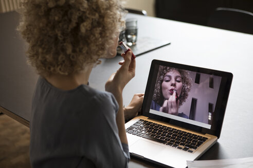 Woman in office applying make-up using laptop monitor as mirror - RBF05566