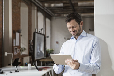 Smiling businessman using tablet in office - RBF05598