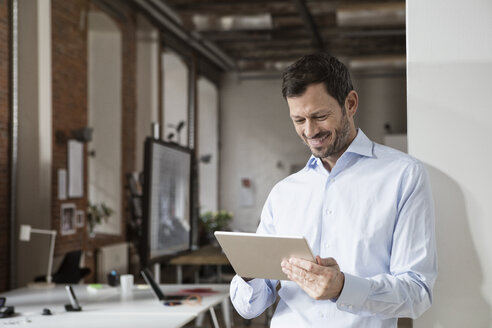 Lächelnder Geschäftsmann mit Tablet im Büro - RBF05598