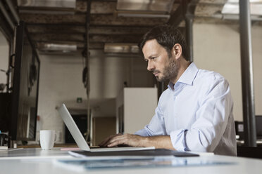 Businessman using laptop in office - RBF05605