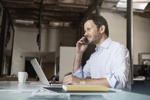 Geschäftsmann am Schreibtisch mit Laptop und Telefon - RBF05606