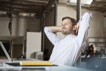 Confident businessman at desk leaning back - RBF05608