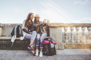 Zwei glückliche junge Frauen auf einer Reise machen ein Selfie mit einem Tablet - KIJF01114