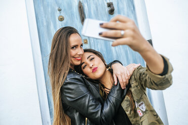 Zwei glückliche junge Frauen machen ein Selfie mit einem Smartphone - KIJF01131