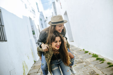 Happy young woman giving friend a piggyback ride - KIJF01136