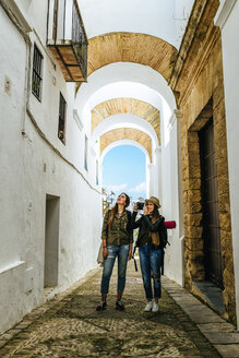 Spanien, Andalusien, Vejer de la Frontera, zwei junge Frauen beim Fotografieren in der Gasse El Callejon de las Monjas - KIJF01149