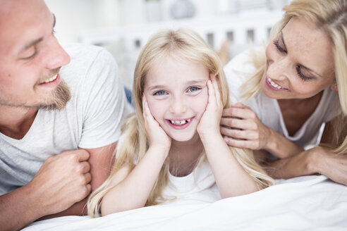 Porträt eines lächelnden Mädchens mit Eltern im Bett - WESTF22529