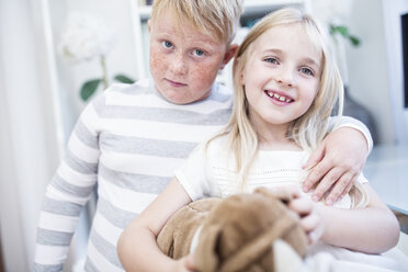 Portait of brother embracing sister holding cuddly toy - WESTF22553