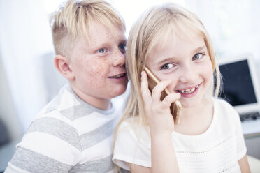 Bruder und Schwester benutzen gemeinsam ein Mobiltelefon - WESTF22560