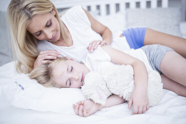 Mother looking at sleeping daughter in bed - WESTF22563