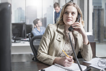 Junge Frau am Schreibtisch im Büro beim Telefonieren - ZEF12493