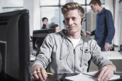 Young man at desk in office wearing a headset stock photo