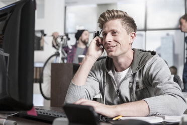 Junger Mann am Schreibtisch im Büro mit einem Headset - ZEF12496