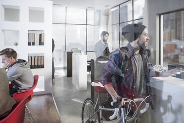 Lässiger Mann mit Fahrrad in modernem Büro - ZEF12504