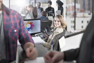 Portrait of smiling woman in busy office - ZEF12510