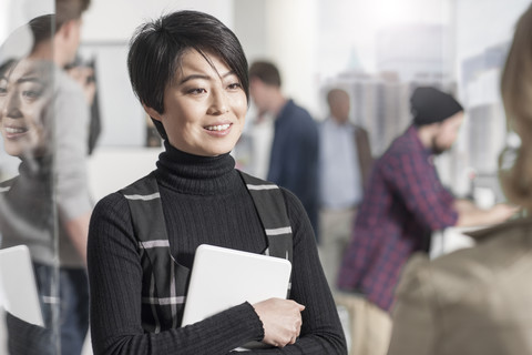 Portrait of smiling woman holding a tablet in office stock photo