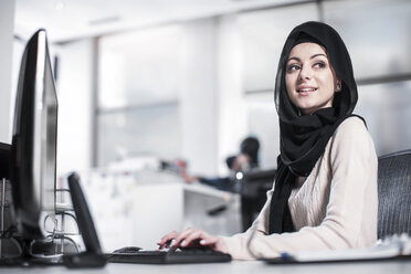 Junge Frau mit Hidschab bei der Arbeit am Schreibtisch im Büro - ZEF12537