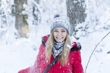 Porträt einer lächelnden jungen Frau bei starkem Schneefall - JUNF00778