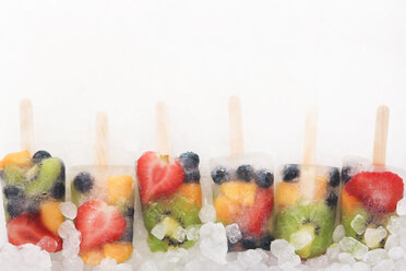 Row of six fruit ice lollies with fresh fruits on white ground - RTBF00612