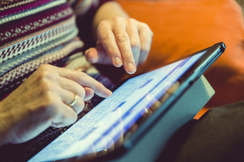 Ältere Frau benutzt Tablet zu Hause, Nahaufnahme, lizenzfreies Stockfoto