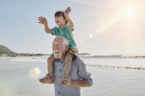 Happy senior man with grandson on his shoulders on the beach - RORF00534