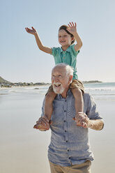 Porträt eines älteren Mannes mit einem glücklichen Enkel auf seinen Schultern am Strand - RORF00536
