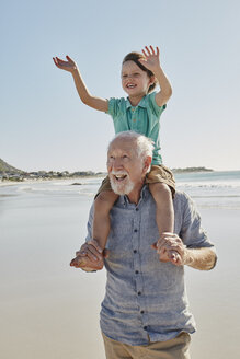Portrait of senior man with happy grandson on his shoulders on the beach - RORF00536