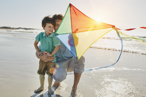 Vater und kleiner Sohn mit Lenkdrachen am Strand, lizenzfreies Stockfoto