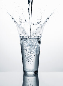 Einfüllen von Wasser in ein Glas vor einem weißen Hintergrund - RORF00572