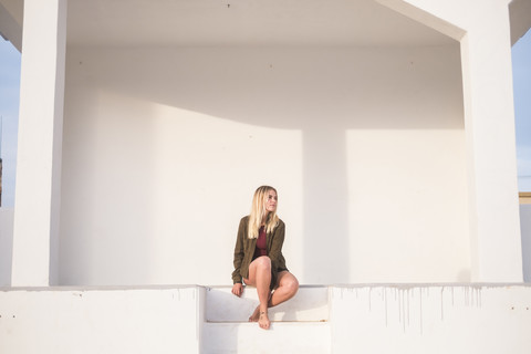 Spanien, Teneriffa, junge blonde Frau auf Stufen sitzend, lizenzfreies Stockfoto