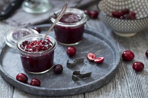 Einmachgläser mit Preiselbeermarmelade und frischen Preiselbeeren - YFF00625