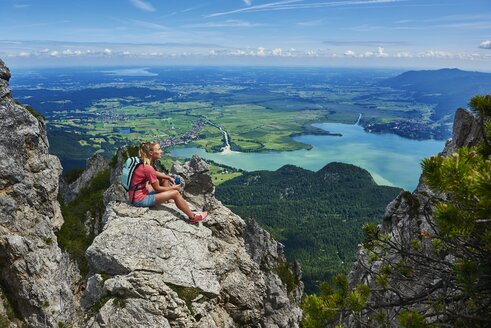 Deutschland, Bayern, Junge Frau, die nach dem Laufen in den Bergen eine Pause einlegt - MRF01685