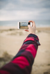 Frauenhand, die den Strand mit einem Smartphone fotografiert - RAEF01682