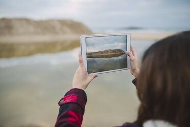 Junge Frau fotografiert mit Tablet am Strand - RAEF01692