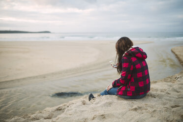 Young woman on the beach looking at cell phone - RAEF01694