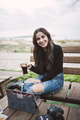 Porträt einer lächelnden jungen Frau mit einem Glas Cola in einem Straßencafé - RAEF01707