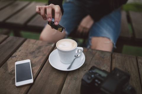 Frau gießt Zucker in eine Tasse Kaffee, Teilansicht, lizenzfreies Stockfoto