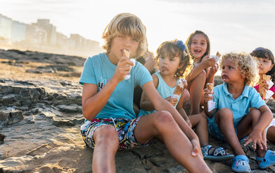 Group of six children eating icecream on the beach - MGOF02820